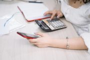 woman using a black and red smartphone and calculator