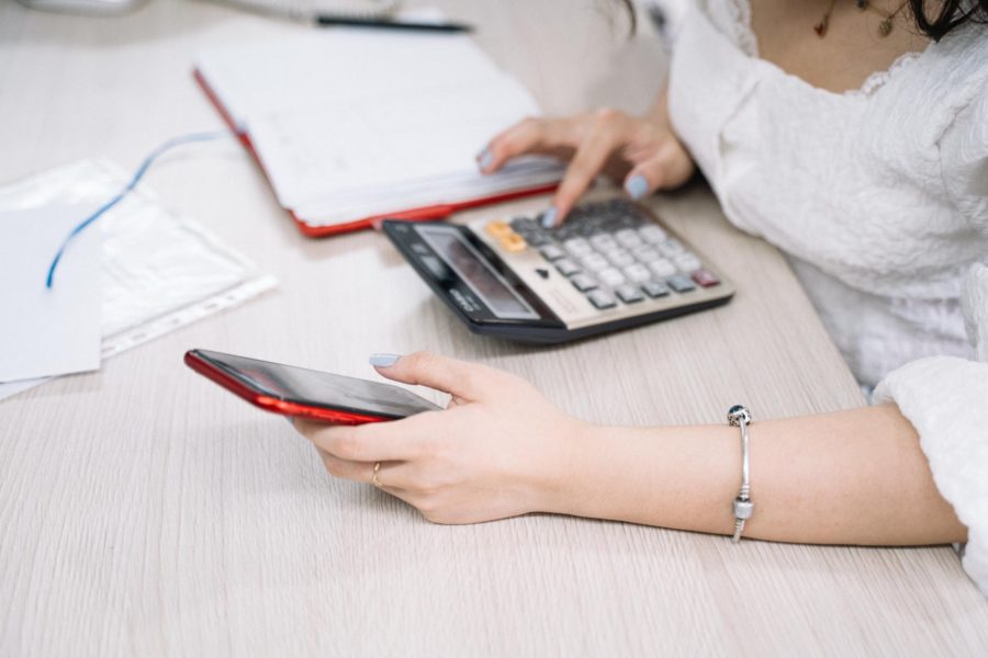 woman using a black and red smartphone and calculator